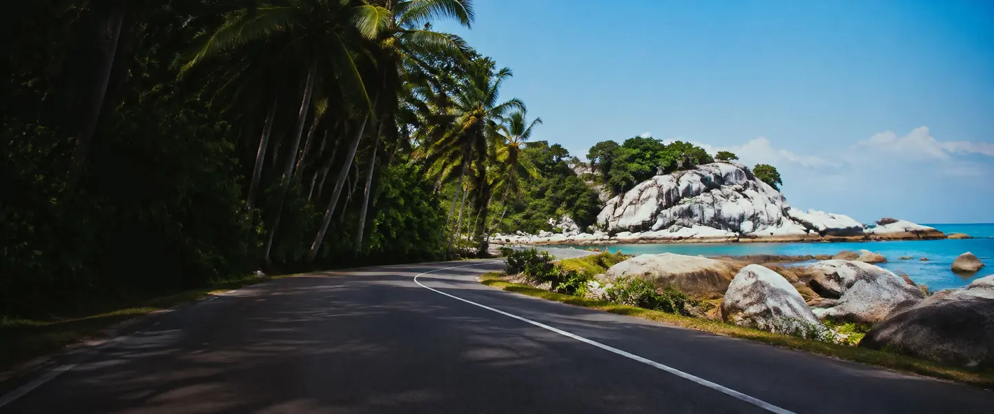 Jalan pesisir sepi di Pulau Belitung dengan batu granit dan laut biru